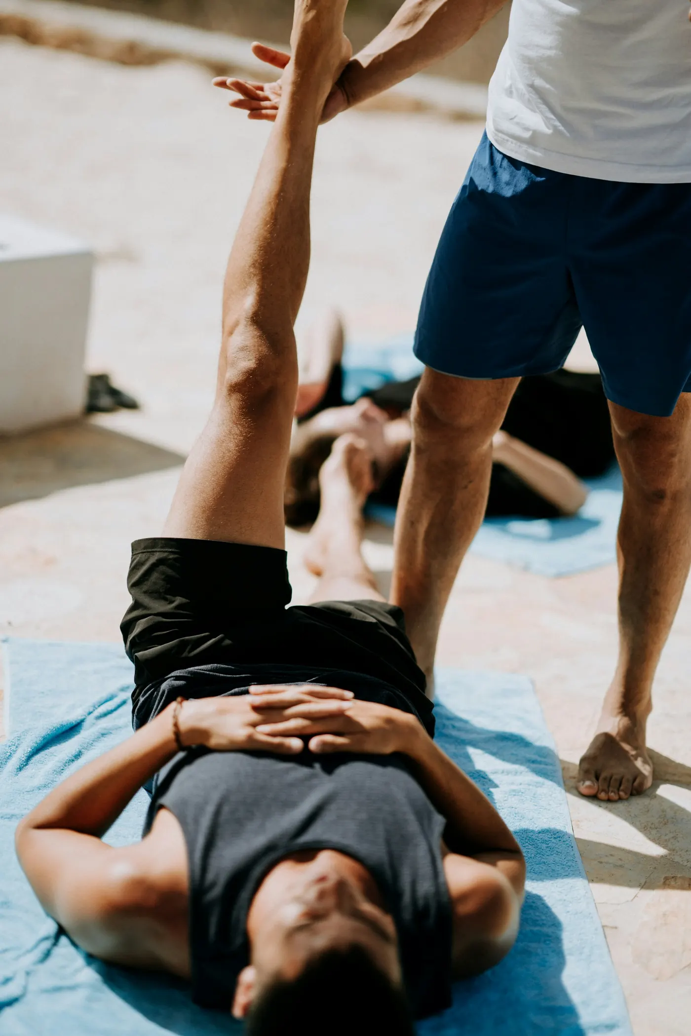 Terapis melakukan peregangan khas Thai Massage pada klien yang mengenakan pakaian longgar.